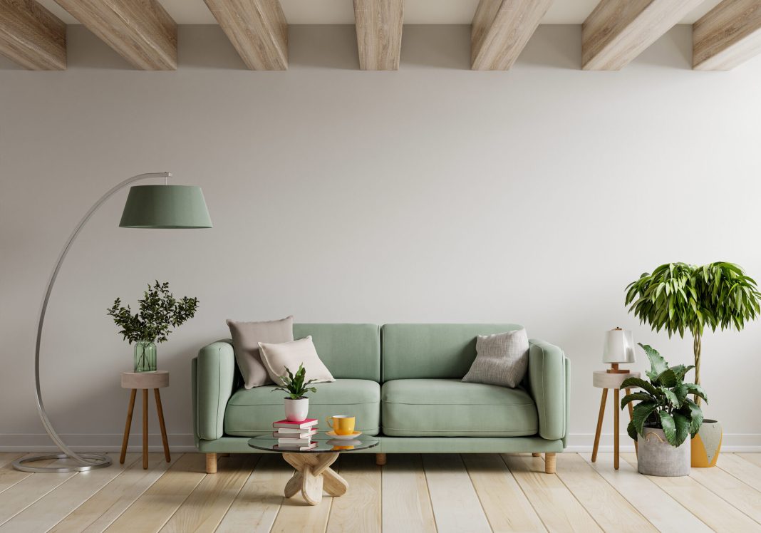 Green sofa in modern apartment interior with empty wall and wooden table.